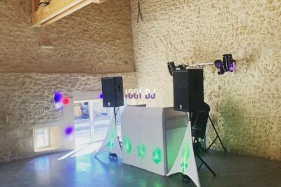 Un DJ mixant de la musique sur une table de mixage dans une salle éclairée par des lumières violettes.