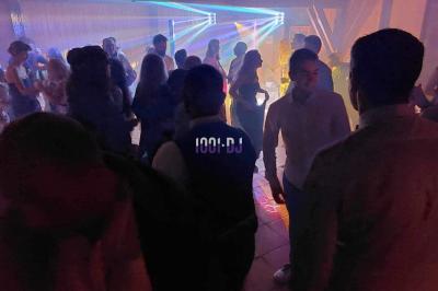 Un DJ mixant de la musique sur une table de mixage dans une salle éclairée par des lumières violettes.