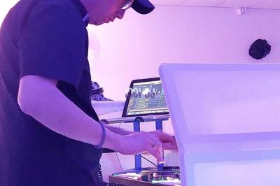 Un DJ mixant de la musique sur une table de mixage dans une salle éclairée par des lumières violettes.