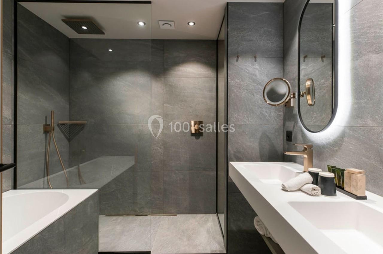 Salle de bain moderne avec douche à l'italienne, baignoire, double vasque et éclairage intégré.