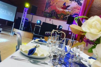 Salle en pierre avec éclairage coloré, scène équipée de projecteurs et écran en fond, ambiance festive.