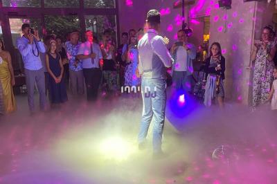 Salle en pierre avec éclairage coloré, scène équipée de projecteurs et écran en fond, ambiance festive.