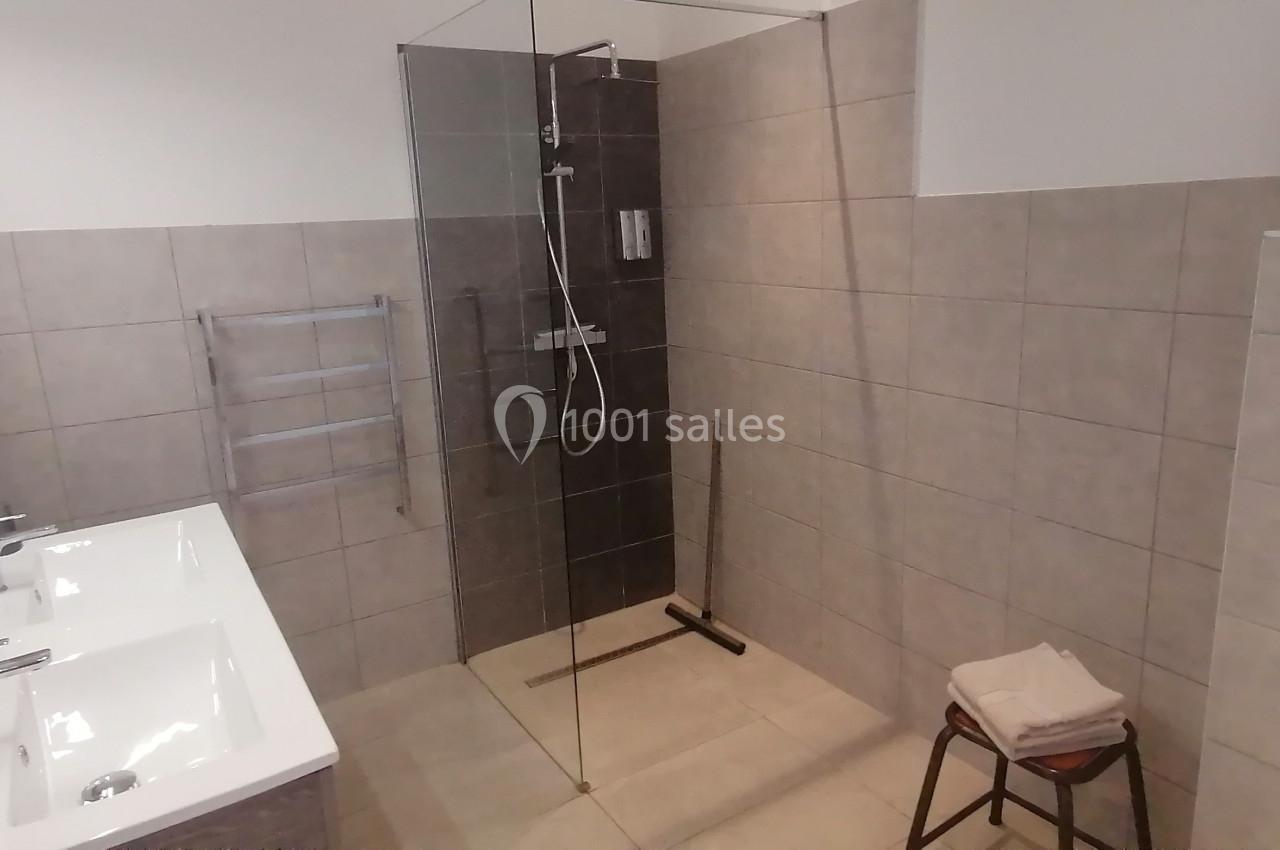 Salle de bain moderne avec douche à l'italienne, lavabo double, carrelage beige et accessoires minimalistes.