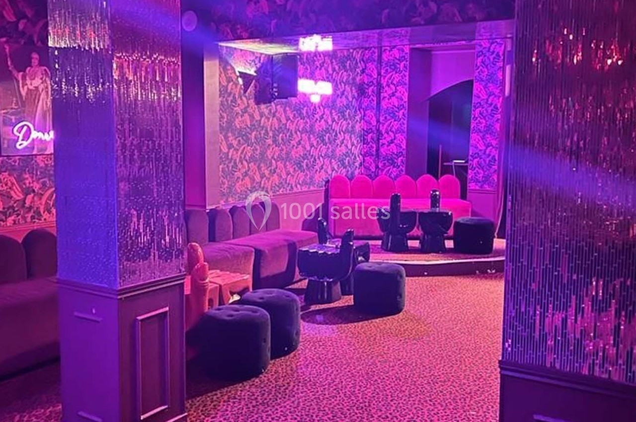 Salle de réception avec banquettes roses, tabourets noirs et éclairage tamisé aux tons violets.