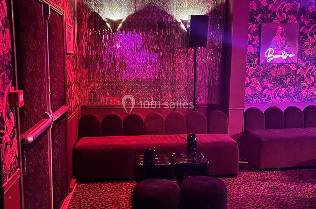Banquette rouge dans un espace intérieur à la décoration tamisée avec éclairage rose et mur texturé.