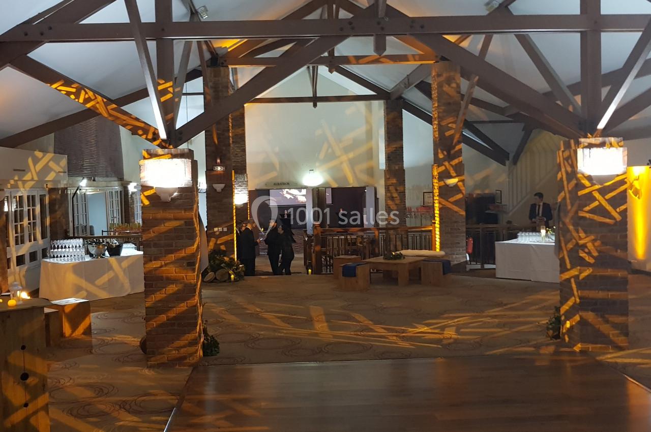 Salle spacieuse avec poutres apparentes, éclairage chaleureux et décorations lumineuses projetées sur les murs.