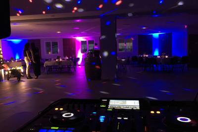 Miniature DJ Patay (Loiret) - Atomix Deejay #10 Un DJ en chemise blanche mixe de la musique sur une console lors d'un événement avec des invités en arrière-plan.