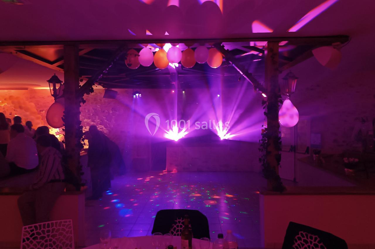 Salle de réception avec éclairage coloré, projecteurs lumineux et décorations suspendues, ambiance festive.