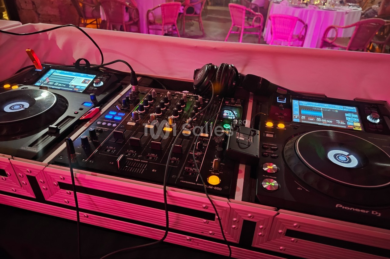 Deux platines DJ et une table de mixage avec des casques, installées dans un espace de réception éclairé.