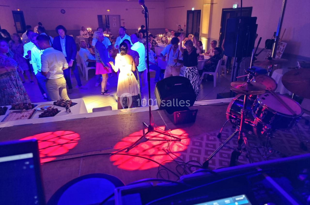 Vue depuis une scène sur une salle de réception où des invités dansent sous des lumières colorées.