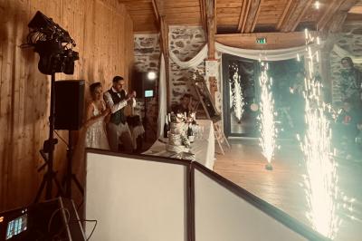 Salle de réception en pierre avec plafond en bois, tables rondes dressées et éclairage chaleureux.