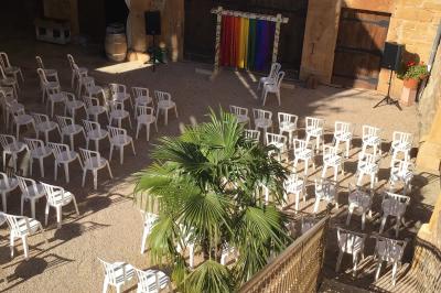 Salle de réception en pierre avec plafond en bois, tables rondes dressées et éclairage chaleureux.