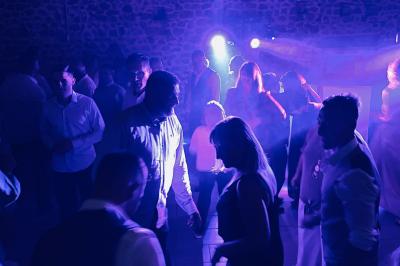 Salle de réception en pierre avec plafond en bois, tables rondes dressées et éclairage chaleureux.