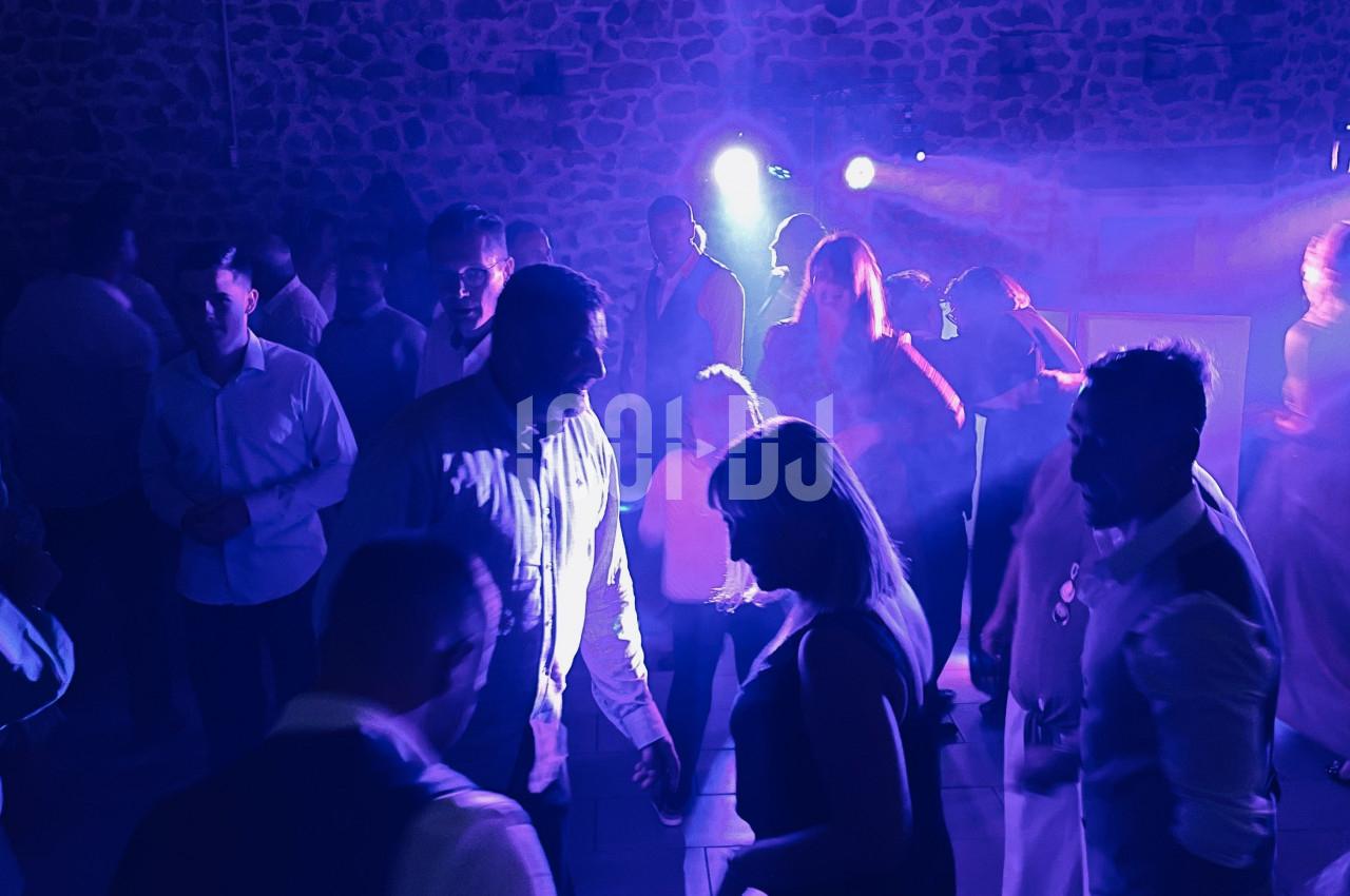 Personnes dansant dans une salle sombre éclairée par des lumières bleues et violettes, ambiance festive.
