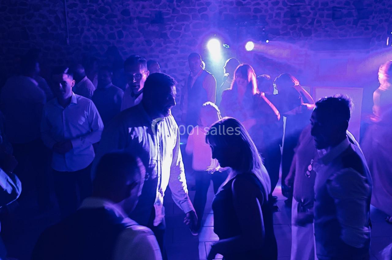 Personnes dansant sous des lumières bleues et violettes dans une salle à l'ambiance festive.