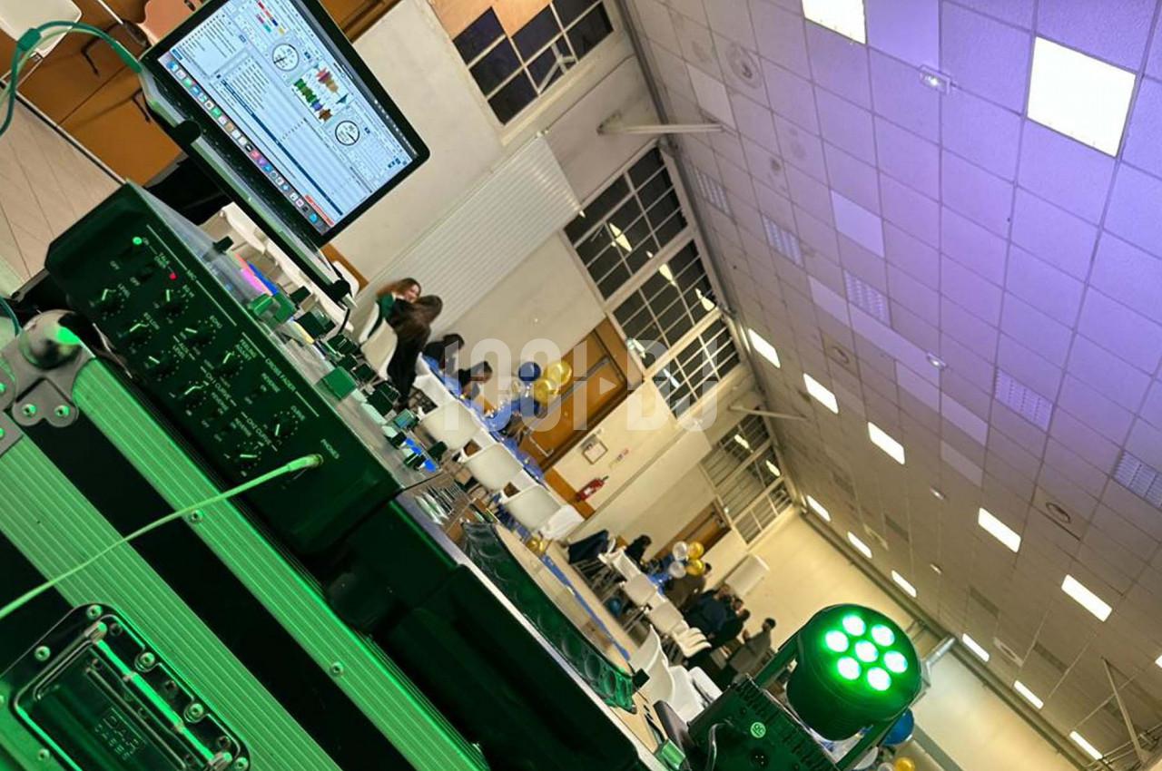 Vue d'une salle de réception avec des tables décorées, un équipement de sonorisation et des invités en arrière-plan.