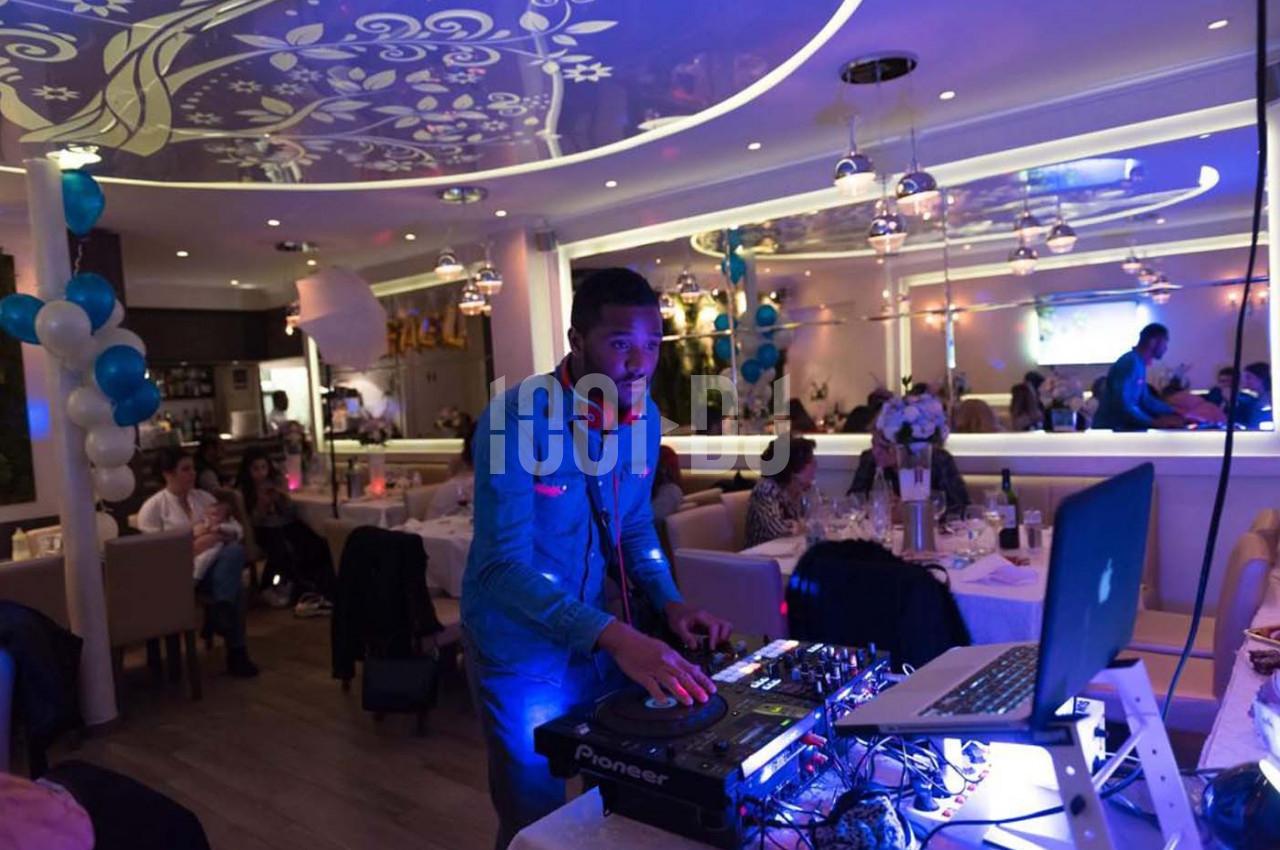 Un DJ mixe de la musique dans un restaurant décoré avec des ballons et des lumières colorées.