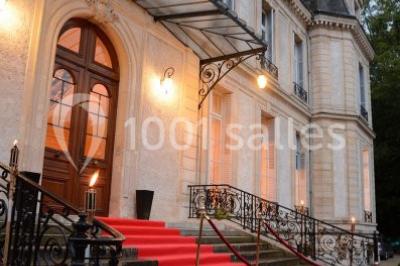 Façade d'un château éclairé par des lumières colorées, vue de nuit avec des silhouettes de personnes devant.
