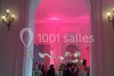 Façade d'un château éclairé par des lumières colorées, vue de nuit avec des silhouettes de personnes devant.