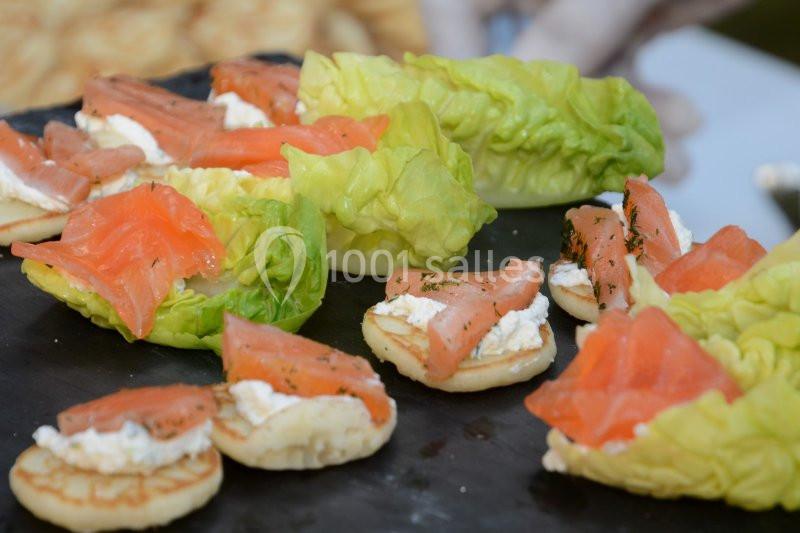 Assortiment de canapés avec saumon fumé, fromage frais et feuilles de salade, disposés sur une ardoise noire.