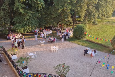 Façade d'un château illuminé la nuit avec une fontaine ornée de statues au premier plan.