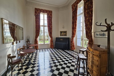 Façade d'un château illuminé la nuit avec une fontaine ornée de statues au premier plan.