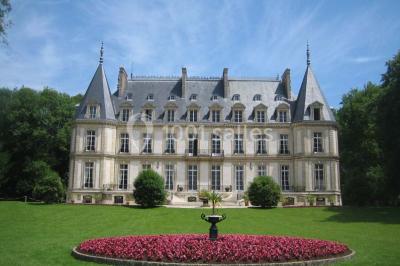 Façade d'un château éclairé par des lumières colorées, vue de nuit avec des silhouettes de personnes devant.