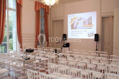Façade d'un château éclairé par des lumières colorées, vue de nuit avec des silhouettes de personnes devant.