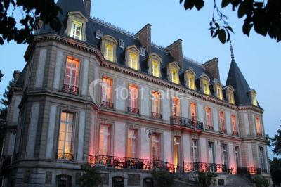Façade d'un château éclairé par des lumières colorées, vue de nuit avec des silhouettes de personnes devant.