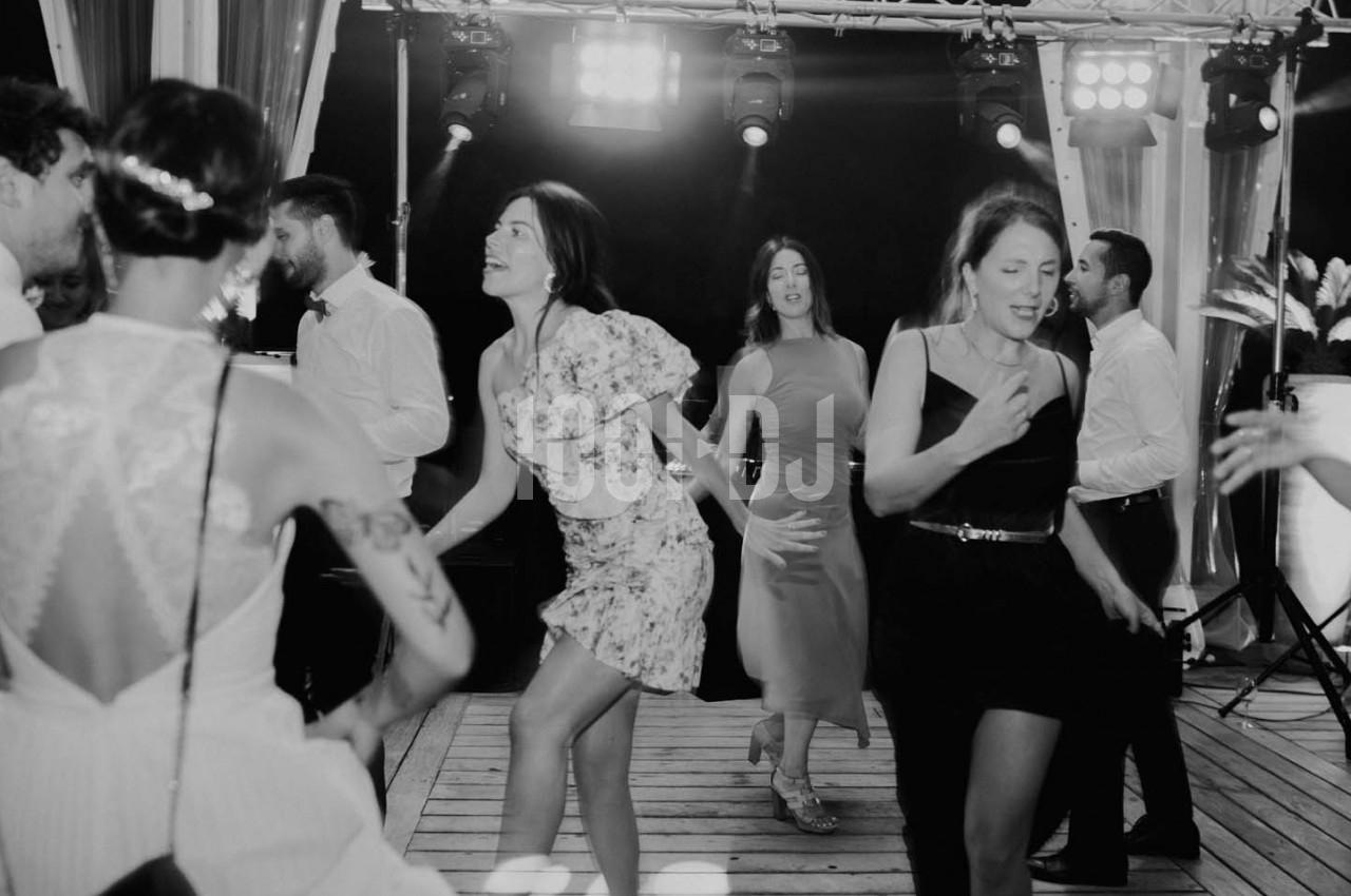Des personnes dansent sur une piste en bois lors d'une soirée festive, éclairée par des projecteurs.