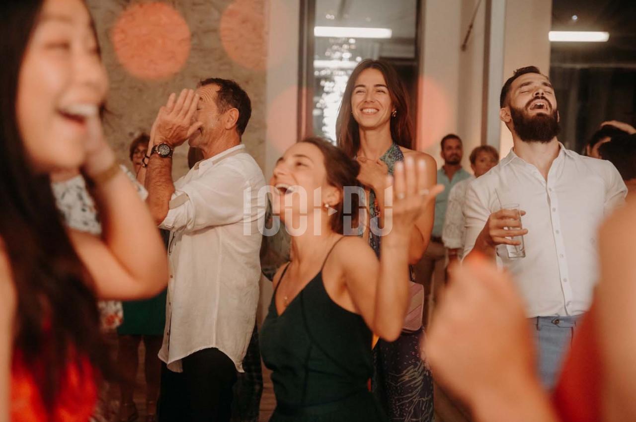 Des personnes souriantes dansent et s'amusent lors d'une soirée dans un espace intérieur éclairé.