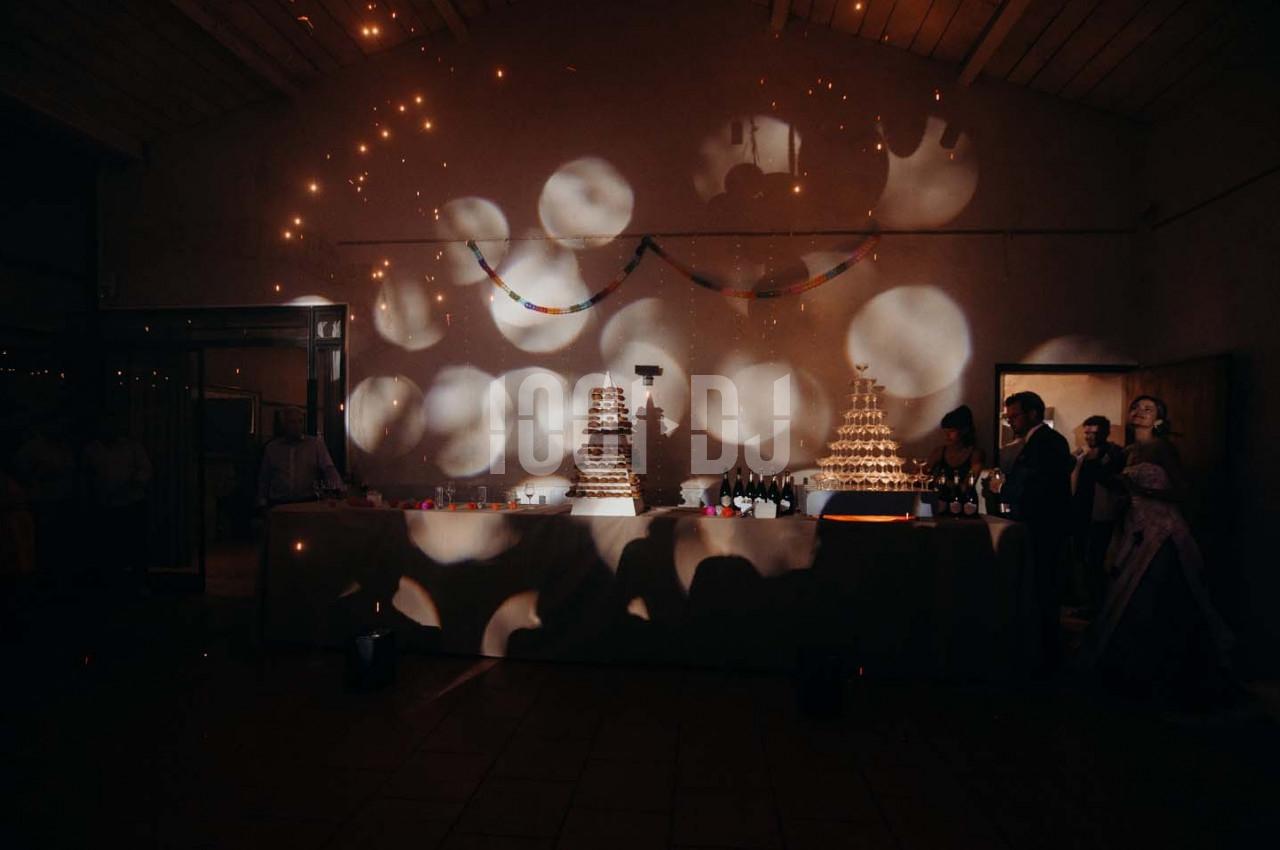 Table décorée avec des pyramides de choux et des bouteilles, éclairée par des lumières tamisées dans une salle sombre.