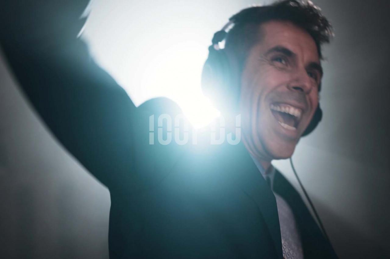 Homme souriant portant un casque audio, éclairé par une lumière vive en arrière-plan.