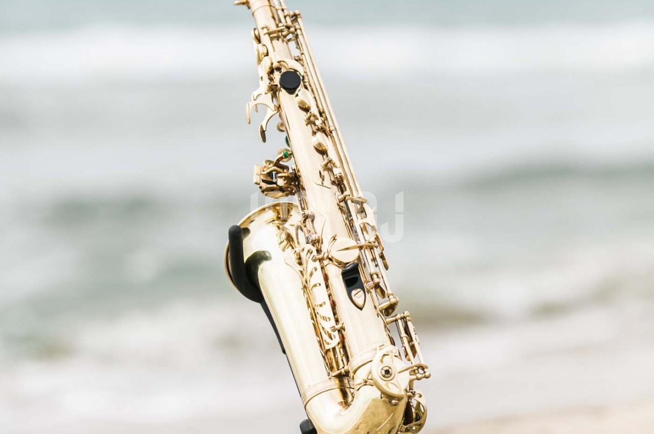 Saxophone doré en gros plan avec un arrière-plan flou de plage et de vagues.