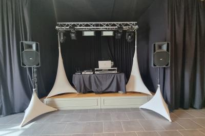 Miniature DJ Bondues (Nord) - Luk Event #3 Des personnes dansent et chantent dans une salle éclairée de lumières colorées, avec un chanteur au premier plan.