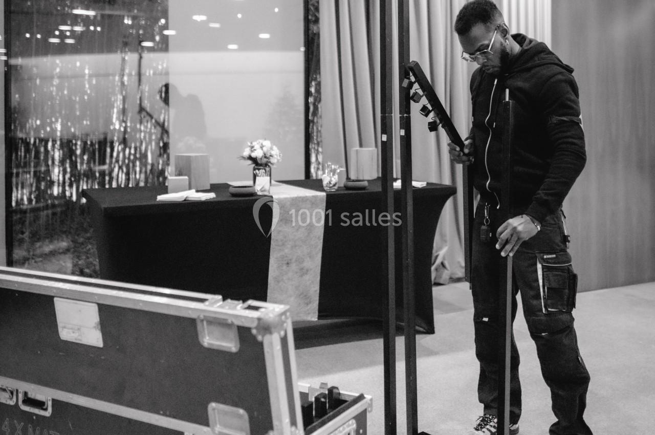 Un technicien installe un équipement audio près d'une table décorée dans une salle intérieure.