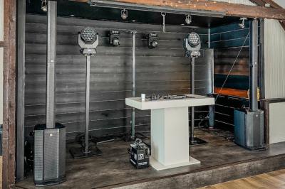 Personnes dansant sous des lumières colorées dans une salle sombre avec une scène équipée de matériel de DJ.