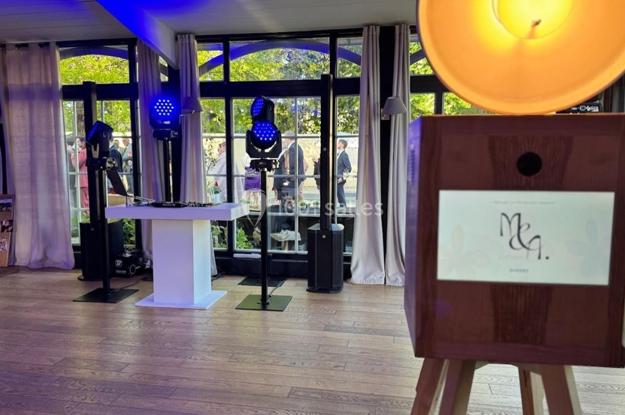 Installation de DJ avec éclairage coloré dans une salle lumineuse, équipée de grandes fenêtres donnant sur un jardin.