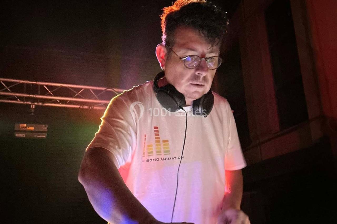 Un DJ portant un casque audio mixe de la musique sur une scène éclairée par des lumières colorées.