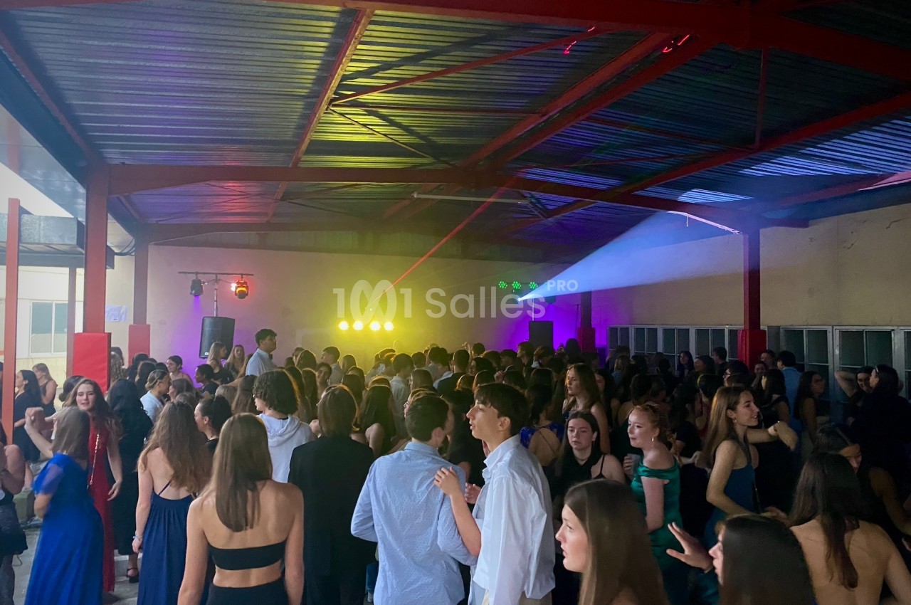 Groupe de jeunes dans une salle couverte, éclairée par des lumières colorées, lors d'une soirée dansante.