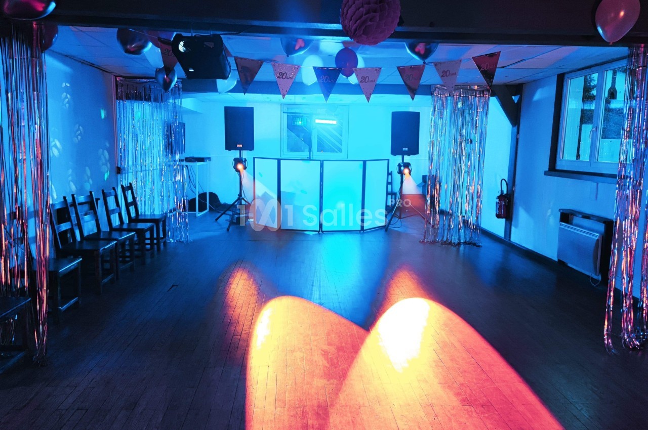 Salle de fête décorée avec guirlandes, éclairage coloré et équipement de sonorisation installé au centre.