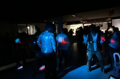 Personnes dansant dans une salle sombre éclairée par des lumières colorées, ambiance festive.