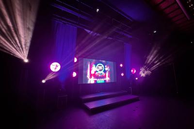 Miniature DJ Clohars-Fouesnant (Finistère) - Breizh Audio #7 Scène éclairée avec projecteurs colorés et écran central affichant des graphismes lumineux dans une ambiance sombre.