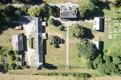 Pelouse verdoyante entourée de grands arbres sous un ciel partiellement nuageux.