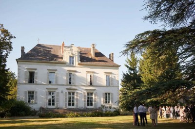 Pelouse verdoyante entourée de grands arbres sous un ciel partiellement nuageux.