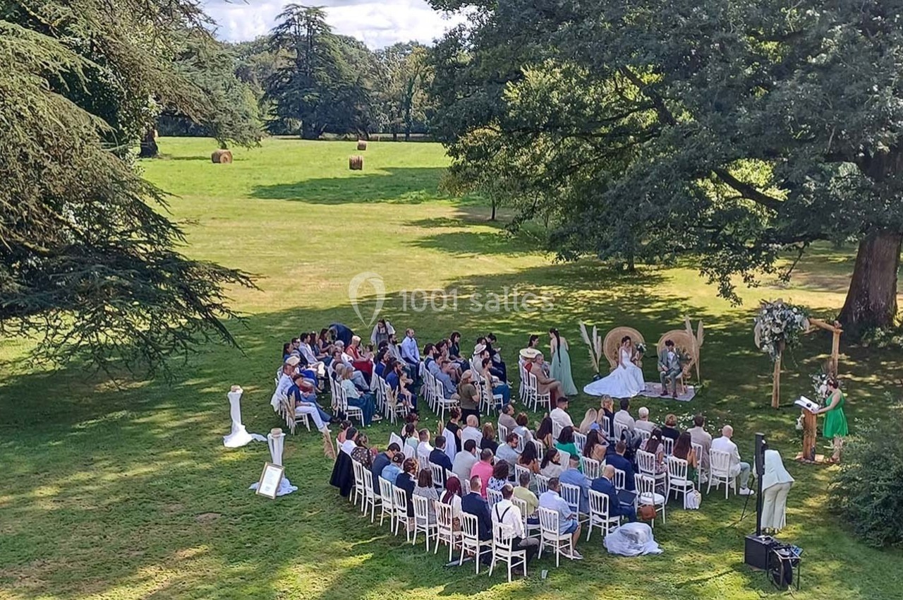 Cérémonie en plein air avec des invités assis en cercle, entourés d'arbres et d'un grand espace vert.