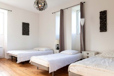 Pelouse verdoyante entourée de grands arbres sous un ciel partiellement nuageux.