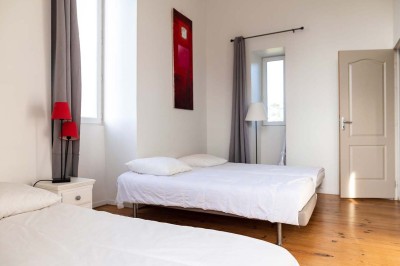 Pelouse verdoyante entourée de grands arbres sous un ciel partiellement nuageux.