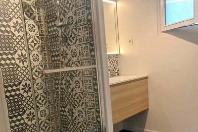 Pelouse verdoyante entourée de grands arbres sous un ciel partiellement nuageux.