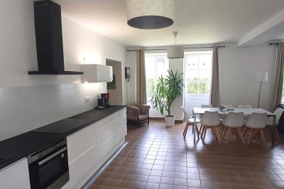 Pelouse verdoyante entourée de grands arbres sous un ciel partiellement nuageux.